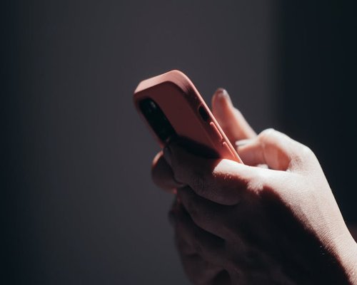 Hands holding a smartphone in a dim environment