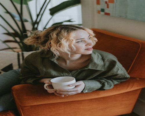 A person resting their eyes sitting on a sofa